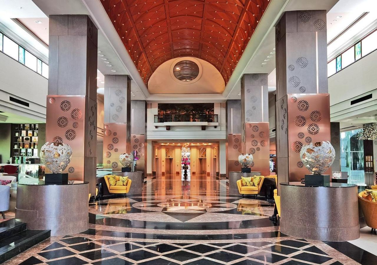 萨马萨玛克利亚酒店 雪邦 外观 照片 The photo shows a luxurious hotel lobby featuring an expansive, open space with high ceilings. The floor is made of polished black and white marble arranged in a geometric pattern. Large, elegant columns support the structure, and the ceiling is ador