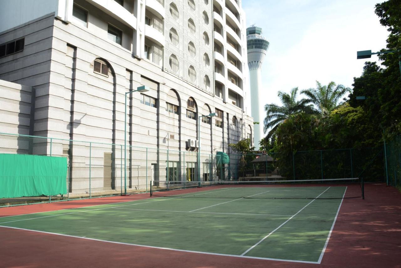 萨马萨玛克利亚酒店 雪邦 外观 照片 The photo shows a tennis court with a green playing surface and red outer borders. In the background, there is a modern building with a white facade, featuring large windows and an architectural design that includes arches. Additionally, a tall tower