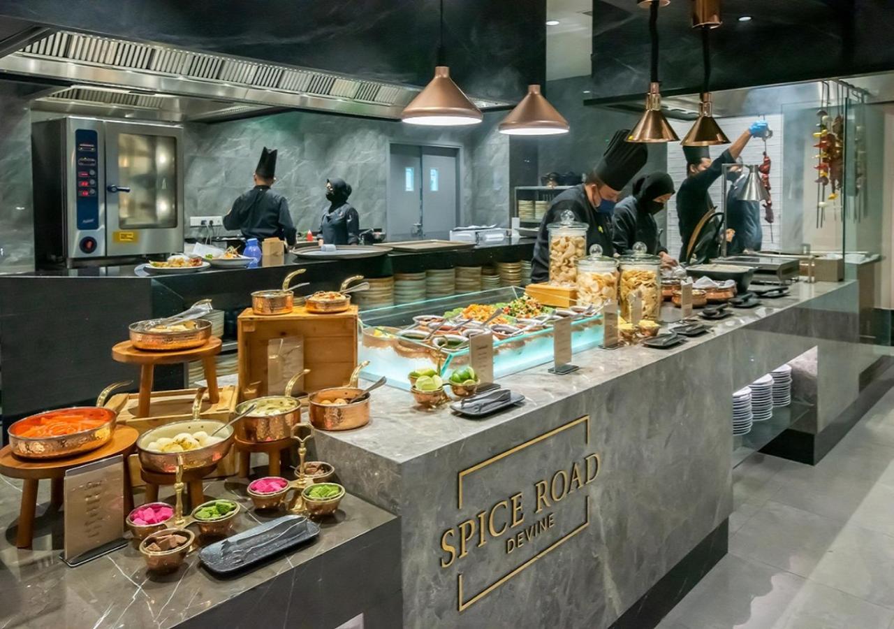 萨马萨玛克利亚酒店 雪邦 外观 照片 The photo depicts a restaurant kitchen or buffet area labeled "Spice Road." The space features a modern design with elements like copper hanging lights and a sleek marble counter. A variety of dishes are displayed on the counter, including colorful a