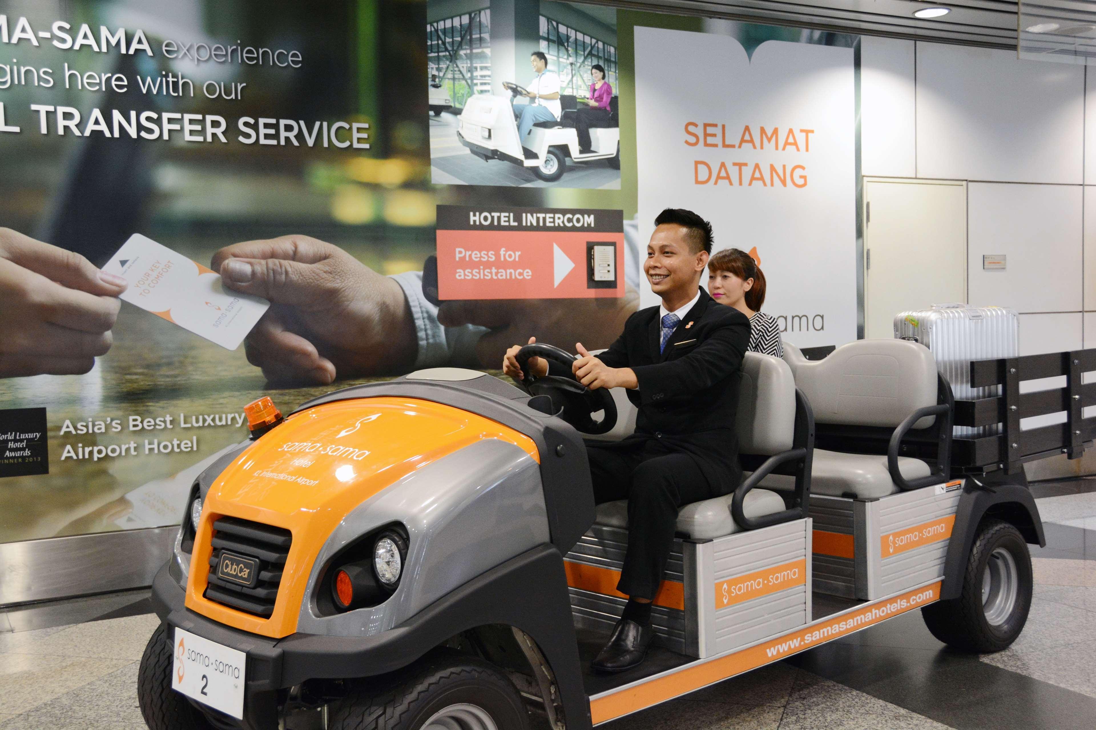 萨马萨玛克利亚酒店 雪邦 外观 照片 The photo shows a man driving a small electric shuttle or golf cart in an airport setting. He appears to be a staff member, likely assisting passengers. There are several empty seats in the cart, suggesting it is used for transporting guests. In the 